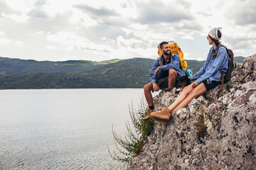 Hikers with backpacks and their doberman  sitting on cliff enjoying at the mountain