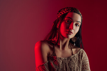 Portrait of young woman in bandana against red background.
