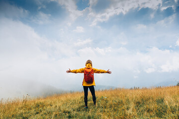 Cheering woman hiker open arms at fall mountains. Happiness Discovery Travel Destination Concept