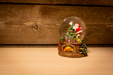Small snow globe with Santa Claus in wooden cabin