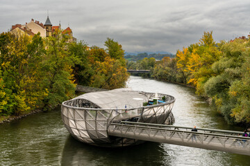 view of the Murinsel artificial island on the river Mur in downtwon Graz with fall foliage colors