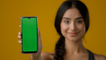 Indian ethnic woman lady girl lady in yellow studio background showing smartphone mobile telephone...