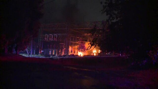 WIDE SHOT OF TRANSFORMER SUBSTATION ON FIRE AT NIGHT