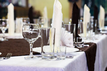 table set in the restaurant. White tablecloths, glasses and shot glasses, close-up, selective focus.