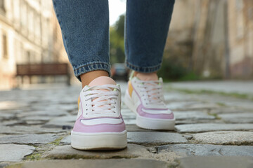 Fototapeta na wymiar Woman in stylish sneakers walking on city street, closeup