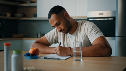 African American man guy male sports athlete nutritionist specialist sitting at table in kitchen...