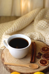 Cup of tea or coffee, various spices, bowl of cookies, tangerines, books, reading glasses and knitted blanket on wooden table. Hygge at home concept, selective focus.