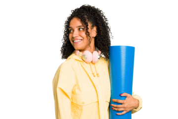 Young sport brazilian woman holding a matt isolated looks aside smiling, cheerful and pleasant.