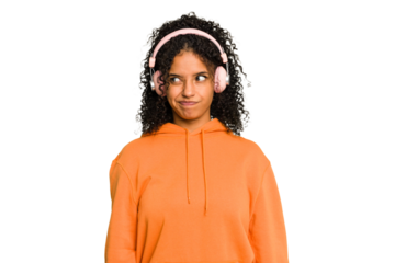 Young Brazilian woman listening to music with headphones isolated confused, feels doubtful and unsure.