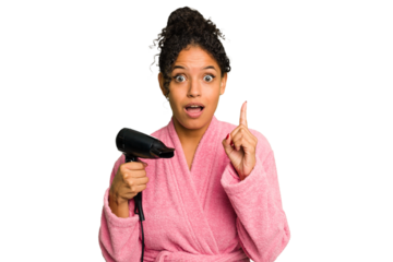 Young brazilian woman wearing a pink bathrobe holding an hairdryer isolated having an idea, inspiration concept.
