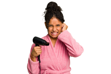 Young brazilian woman wearing a pink bathrobe holding an hairdryer isolated covering ears with hands.