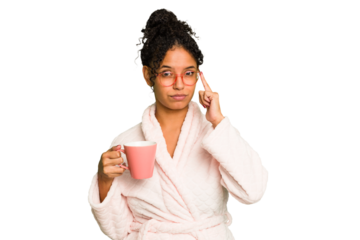Young brazilian woman wearing a pajama holding a cup isolated pointing temple with finger, thinking, focused on a task.