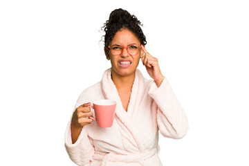 Young brazilian woman wearing a pajama holding a cup isolated showing a disappointment gesture with forefinger.