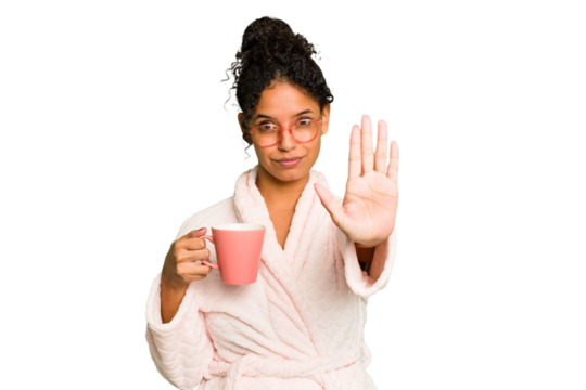 Young brazilian woman wearing a pajama holding a cup isolated standing with outstretched hand showing stop sign, preventing you.