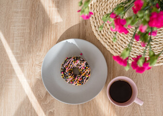 Cozy breakfast. Cup of coffee, pink donut and flowers on the table. Weekend breakfast, relax, girls...