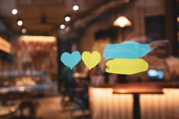 Yellow blue hearts hand-painted on cafe, store window glass. Support for Ukraine