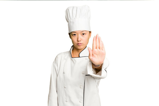 Young asian cook woman isolated standing with outstretched hand showing stop sign, preventing you.