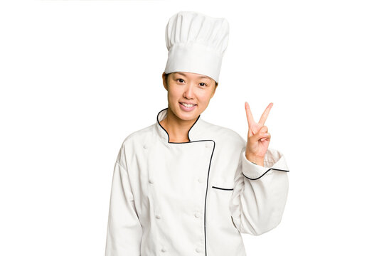 Young asian cook woman isolated joyful and carefree showing a peace symbol with fingers.