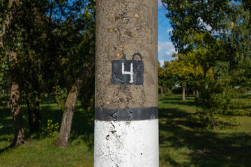 The number 4 is drawn with white paint. Number four on a concrete pillar. Summer sunny day