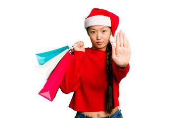 Young asian woman shopping a christmas presents isolated Young asian woman shopping a christmas presents isolated standing with outstretched hand showing stop sign, preventing you.