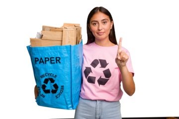 Young caucasian woman holding a recycling bag full of paper to recycle isolated showing number one with finger.