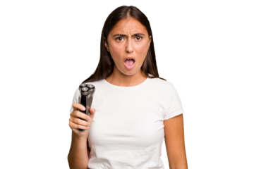 Young caucasian woman holding a razor isolated screaming very angry and aggressive.