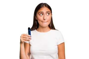 Young caucasian woman holding a electronic cigarette confused, feels doubtful and unsure.