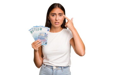 Young caucasian woman holding a banknotes isolated showing a disappointment gesture with forefinger.
