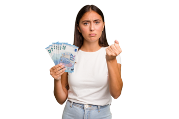 Young caucasian woman holding a banknotes isolated showing fist to camera, aggressive facial expression.
