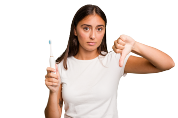 Young caucasian woman holding an electric toothbrush isolated showing a dislike gesture, thumbs down. Disagreement concept.