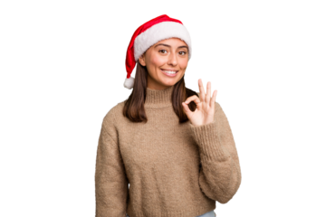 Young caucasian woman celebrating christmas wearing a santa hat isolated cheerful and confident showing ok gesture.