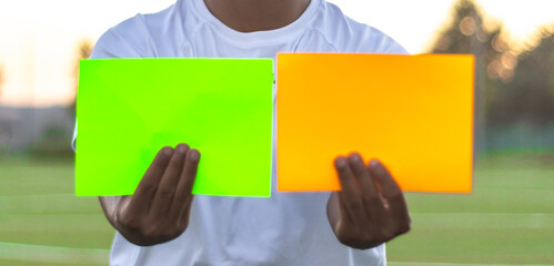 Soccer referee taking out two cards on the field. Front view of soccer referee taking out cards.
