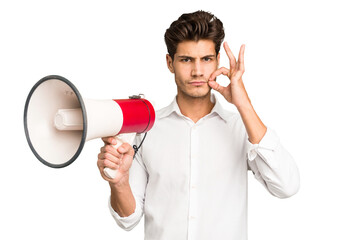 Young caucasian man holding megaphone isolated with fingers on lips keeping a secret.