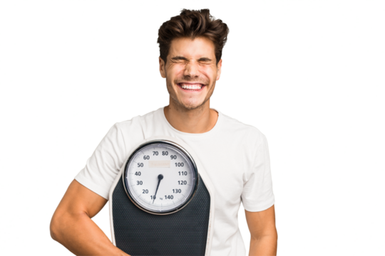 Young caucasian man holding a scale isolated laughing and having fun.