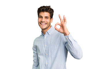 Young caucasian handsome man isolated winks an eye and holds an okay gesture with hand.