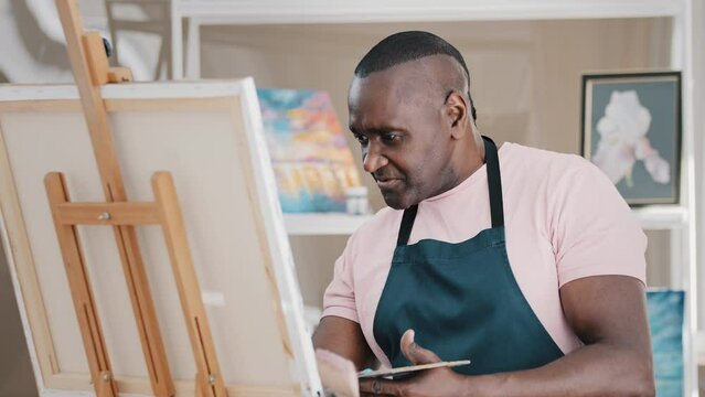 African American old senior 50s middle-aged male teacher man painter drawing painting picture on canvas in studio on lesson class of paint draw explain creative idea talking smiling inspired by art