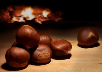 Batch of chestnuts on a table with fire behind