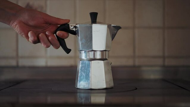 Close-up shot of a vintage silver moka pot on the farmhouse stove. Italian way of black coffee preparation. Geyser coffee maker for delicious coffee at home. Cosy autumn evenings. 