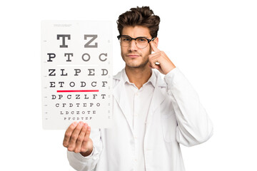 Young caucasian oculist man holding a optometry test isolated