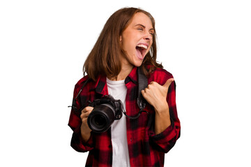 Fototapeta premium Young photographer caucasian woman isolated points with thumb finger away, laughing and carefree.