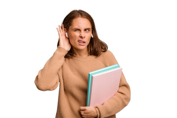 Young student woman holding a books isolated trying to listening a gossip.