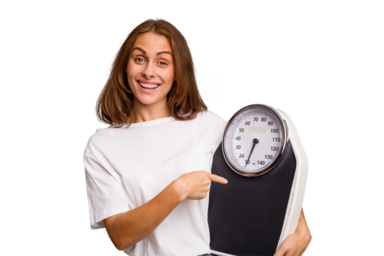 Young caucasian woman holding a scale and measure tape isolated smiling and pointing aside, showing something at blank space.