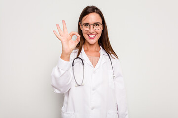 Young doctor woman isolated on white background cheerful and confident showing ok gesture.