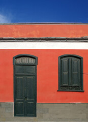Steinbau mit roter Wand mit Tür und Fensterladen