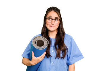 Young caucasian physiotherapist woman holding a mat isolated isolated on green chroma background confused, feels doubtful and unsure.