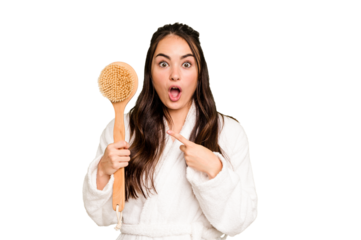 Young caucasian woman holding shower brush isolated on green chroma background pointing to the side