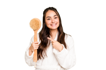 Young caucasian woman holding shower brush isolated on green chroma background smiling and pointing aside, showing something at blank space.