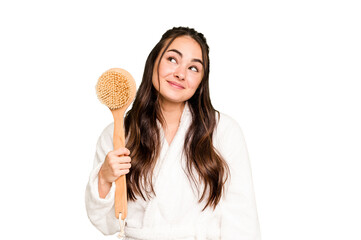 Young caucasian woman holding shower brush isolated on green chroma background dreaming of...