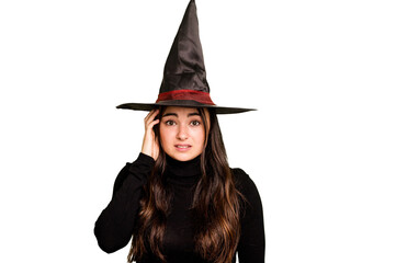 Young caucasian woman dressed as a witch isolated on green chroma background being shocked, she has remembered important meeting.