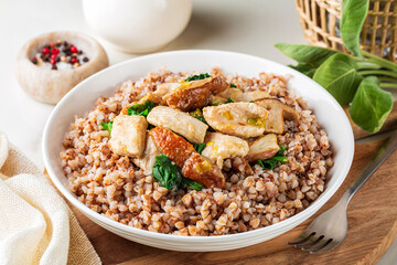 Close-up of boiled buckwheat with porcini mushrooms, turkey meat, spinach. Dinner table, healthy food concept.